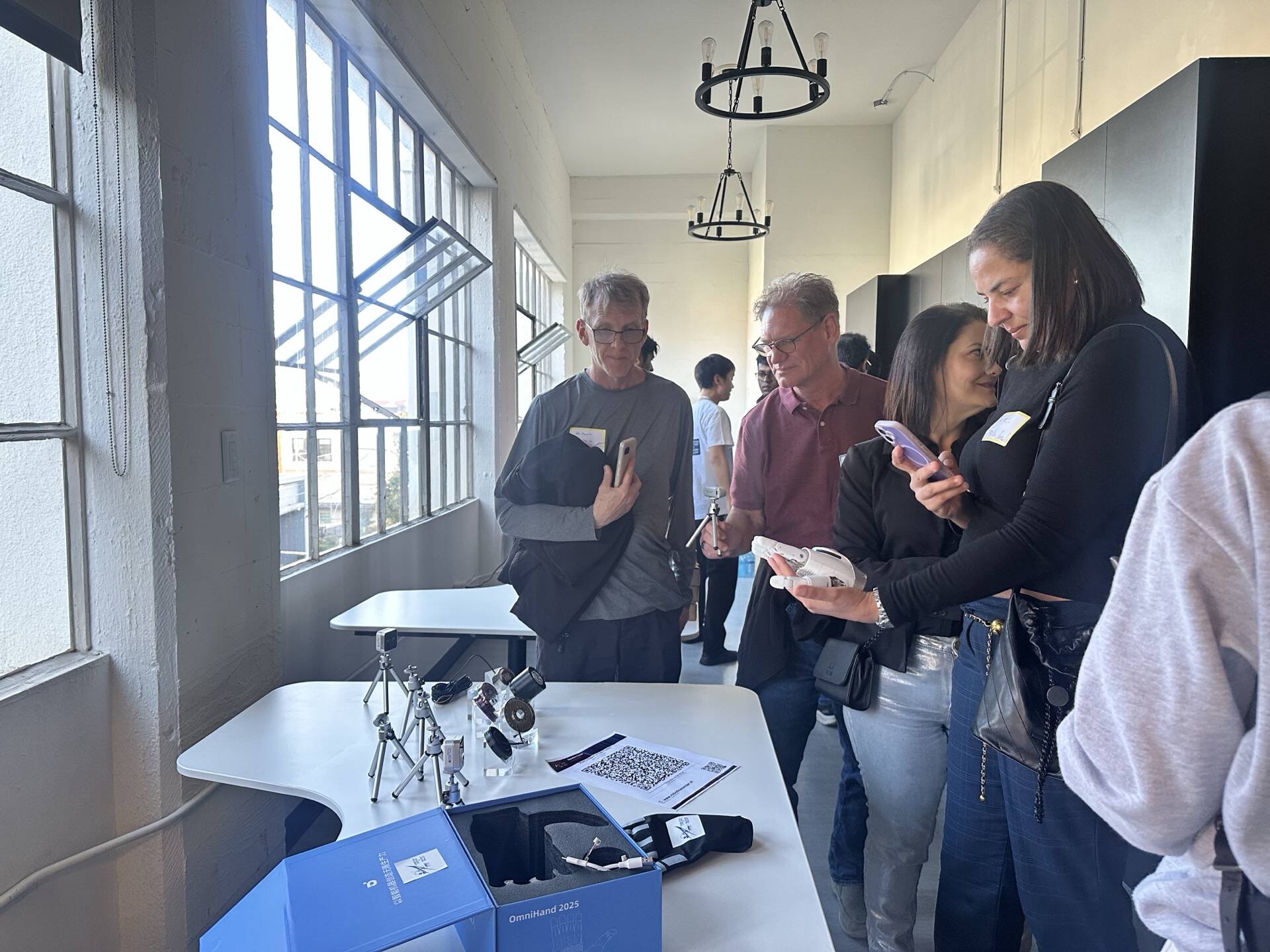 Attendees examining OmniHand glove and camera rig at SVRC May 8 2026 meetup demo table
