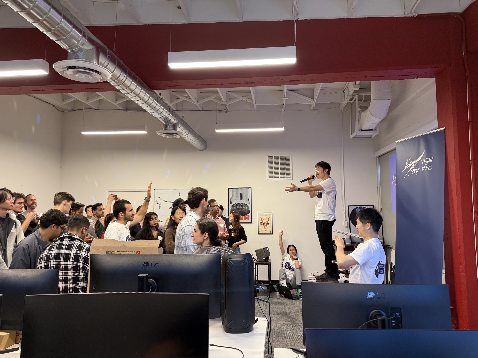 Jerry Huang presenting to packed crowd at SVRC May 2026 meetup, Robotics Center banner visible